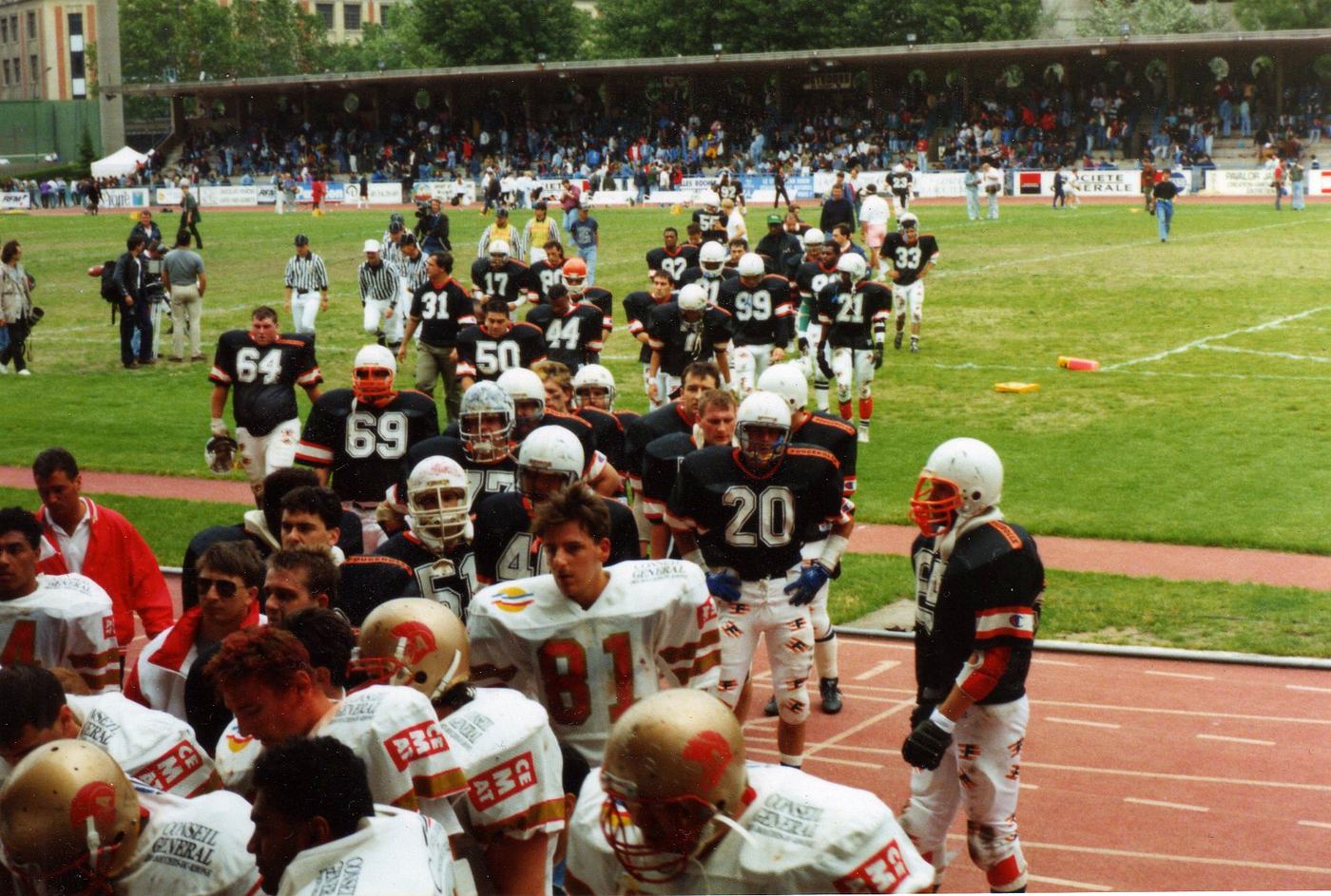 Les Castors de Paris quittent le terrain en maillot bleu nuit à liserés orange, tribunes garnies, championnat de France de football américain, années 1990